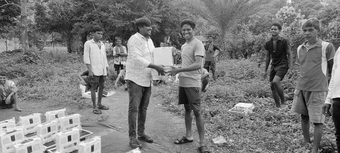 Ministry worker handing a solar light kit to a villager as neighbors gather.